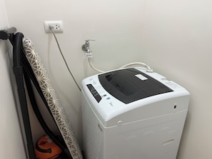 Un climatiseur portatif blanc, doté d’un panneau de commande, branché sur une prise de courant et muni d’un tuyau flexible.