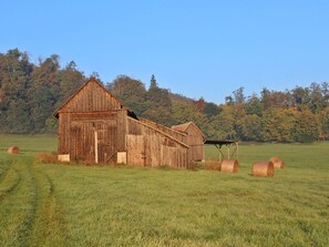 Ein rustikales Bauernhaus mit Holzfassade, Heuballen und blauem Himmel.