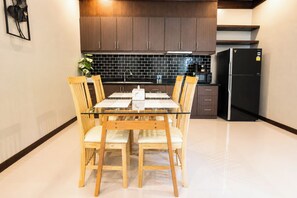Eine moderne Küche mit dunklen Holzschränken, einer schwarzen Küchenrückwand und einem schwarzen Kühlschrank.