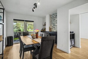 A modern kitchen with a stone backsplash, a dining area with a wooden table and black chairs, and a view of a garden through a sliding glass door. - Spacious Modern 3BR Home with Garage. Monthly Stays, Near DTC,Kid & Pet Friendly (Denver)