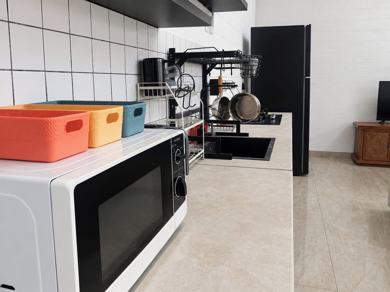 A kitchen with a microwave, a dish rack, and a black refrigerator.