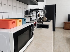 Una cocina con microondas, escurreplatos y un refrigerador negro.