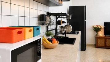 A modern kitchen with a microwave, a fruit bowl, and a dish rack.
