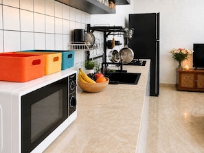 Een moderne keuken met een magnetron, een fruitschaal en een afdruiprek.