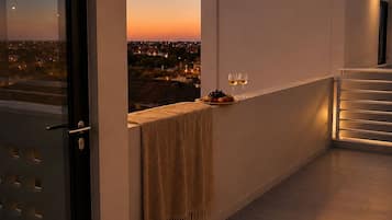 A balcony with a view of a sunset, a towel, and two glasses of wine.