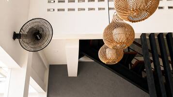 A modern interior with a staircase, a wall-mounted fan, and a hanging light fixture.