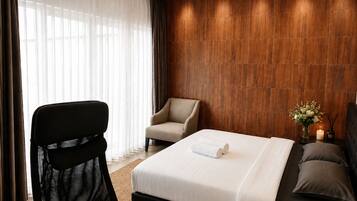 Een hotelkamer met een bed, een stoel, een bank en een houten wand.