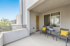 Ein Balkon mit Geländer, einer Tür und zwei Stühlen mit Kissen.