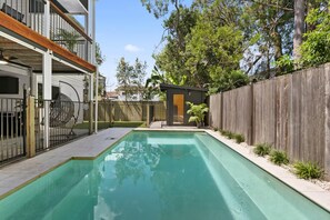 A swimming pool with a wooden deck, a fenced area, and a small structure. - Charming & Modern Resort Living (Chelmer)