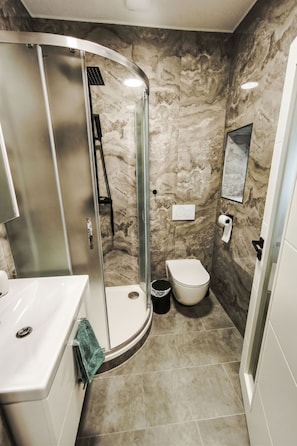 A bathroom with a curved shower enclosure, a toilet, and a sink. - Rychory by Interhome (Zaclér)