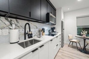 A modern kitchen with a marble backsplash, black cabinets, a stainless steel sink, and a built-in microwave. - 2-bedroom Duo apartment in marvelous Dallas with AC and fitness room (Dallas)