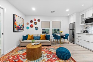 A modern kitchen with white cabinets, a stainless steel refrigerator, and a dining area with a round table and blue chairs. - 2-bedroom Duo apartment in marvelous Dallas with AC and fitness room (Dallas)