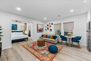 Una sala moderna con cama, sofá, mesa de comedor y sillas.