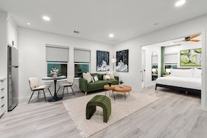A modern hotel room with a green sofa, a round dining table, a bed with a white duvet, and artwork on the walls. - 2-bedroom Duo apartment in marvelous Dallas with AC and fitness room (Dallas)