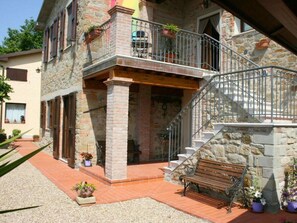 A stone building with a balcony, a staircase, and a bench. - Villa Agriturismo Arcobaleno (Loro Ciuffenna)