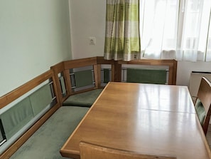 A dining area with a wooden table and green cushioned chairs. - Schwaighof by Interhome (Auffach)