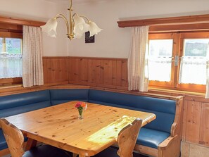 A corner room with a wooden table and blue cushioned bench seating. - Schwaighof by Interhome (Auffach)