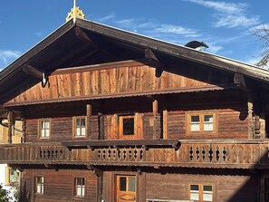 Un bâtiment en bois à deux étages, doté d’un balcon, de nombreuses fenêtres et d’une structure de toit décorative.