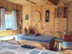 A wooden cabin interior with a bed, a small table, and a window with curtains. - Schwaighof by Interhome (Auffach)