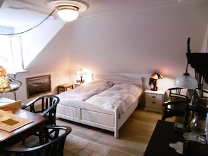 A bedroom with a bed, bedside tables, a desk, chairs, and a lamp. - Holiday Apartment With 1 Bedroom (Lindau)