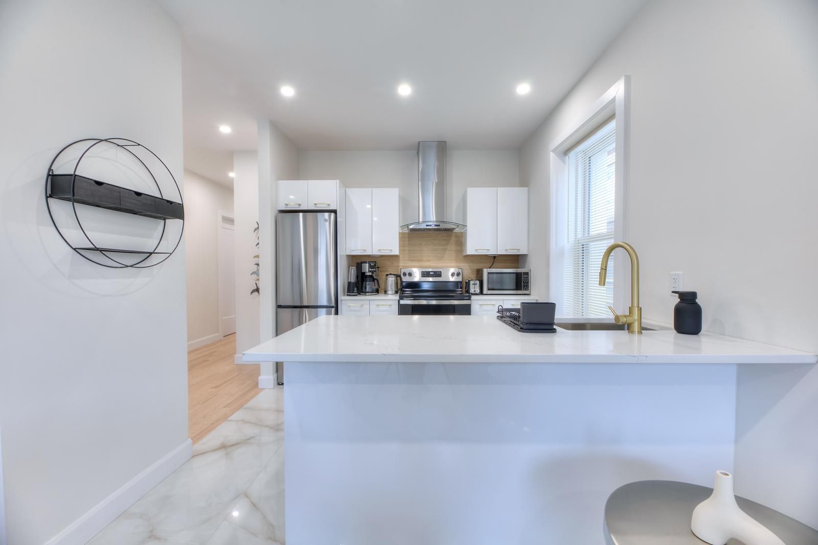 A modern kitchen with a central island, stainless steel appliances, and a white color scheme.