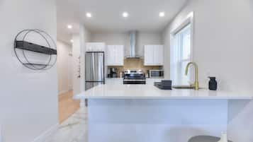A modern kitchen with a central island, stainless steel appliances, and a white color scheme.
