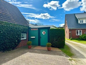 A residential property with a green door, brick walls, and a paved driveway. - North Sea Room 03 (Nieblum)