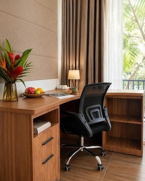 A wooden desk with a black office chair, a vase with flowers, and a window with curtains. - 1 Bedroom Norke Villa Gianyar (Gianyar)
