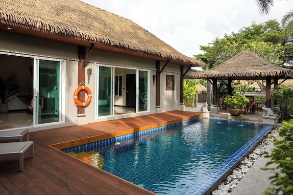 A poolside area with a wooden deck, a thatched-roof structure, and a lifebuoy.