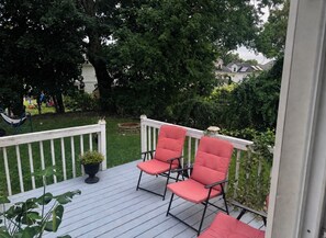 A wooden deck with two red chairs and a potted plant. - Charming 4-bedroom duplex (Manchester)