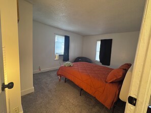 A bedroom with a single bed, two windows, and a door. - Charming 4-bedroom duplex (Manchester)