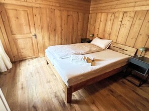 A wooden-paneled room with a bed, a nightstand, and a door. - Maloja Alpine Lodge by Interhome (Maloja)