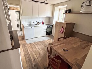 A compact kitchen with white cabinets, a built-in oven, and a small dining table with chairs. - Maloja Alpine Lodge by Interhome (Maloja)