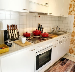 A kitchen with white cabinets, a stove, and a sink. - Ascona Vacation Rental 200 meters from Lake Maggiore (Ascona)