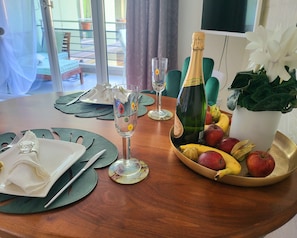 A dining table set with plates, cutlery, glasses, a bottle of champagne, and a fruit bowl. - Ascona Vacation Rental 200 meters from Lake Maggiore (Ascona)