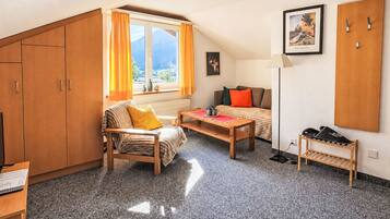 A cozy room with a bed, a chair, a table, and a wardrobe.
