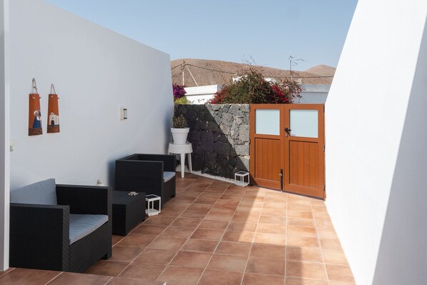 A patio with outdoor furniture, a stone wall, and a wooden gate. - Your Loft in the Heart of Lanzarote: Charm, Tranquility, and Volcanoes (TINAJO)