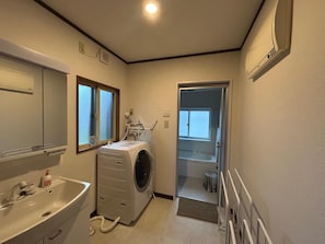 Une petite buanderie équipée d’un lave-linge, d’un évier et d’une fenêtre.