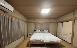 Une chambre avec un lit, une petite table de chevet, un climatiseur fixé au mur et des portes coulissantes.