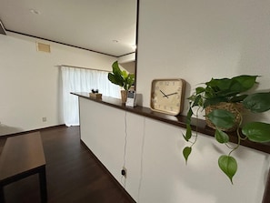 Un espace d’accueil avec un comptoir en bois, une horloge murale et des plantes en pot.