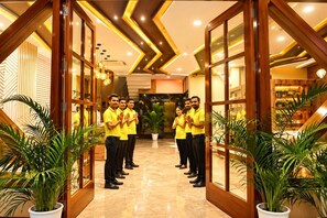 A hotel lobby with a modern design, featuring a central reception area, potted plants, and a geometric ceiling pattern. - The Abhyudyam Ganga (Haridwar)
