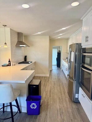 A modern kitchen with a central island, stainless steel appliances, and a dark blue recycling bin. - Private Arcadia-Phoenix Escape with Resort-Style Backyard (Phoenix)
