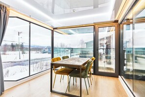 A modern interior with a dining area, large windows, and a view of a snowy landscape. - STRADDIE ISLAND【50%-60% OFF for 7+ Nights | Trailer House & Sauna】 (ニセコ町)