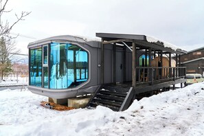 A modern cabin with large windows, a wooden deck, and a snowy landscape. - STRADDIE ISLAND【50%-60% OFF for 7+ Nights | Trailer House & Sauna】 (ニセコ町)