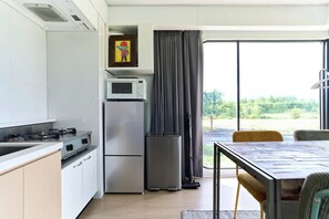 A modern kitchen with a built-in microwave, a stainless steel refrigerator, and a dining area with a table and chairs. - STRADDIE ISLAND【50%-60% OFF for 7+ Nights | Trailer House & Sauna】 (ニセコ町)