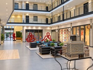 En rummelig lobby med siddeområde, café og en modelbygning.