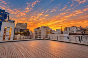 Una terraza en la azotea con el horizonte de la ciudad al atardecer.