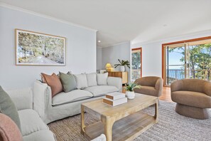 Een woonkamer met een bank, fauteuils, een bijzettafeltje en een schilderij aan de muur.