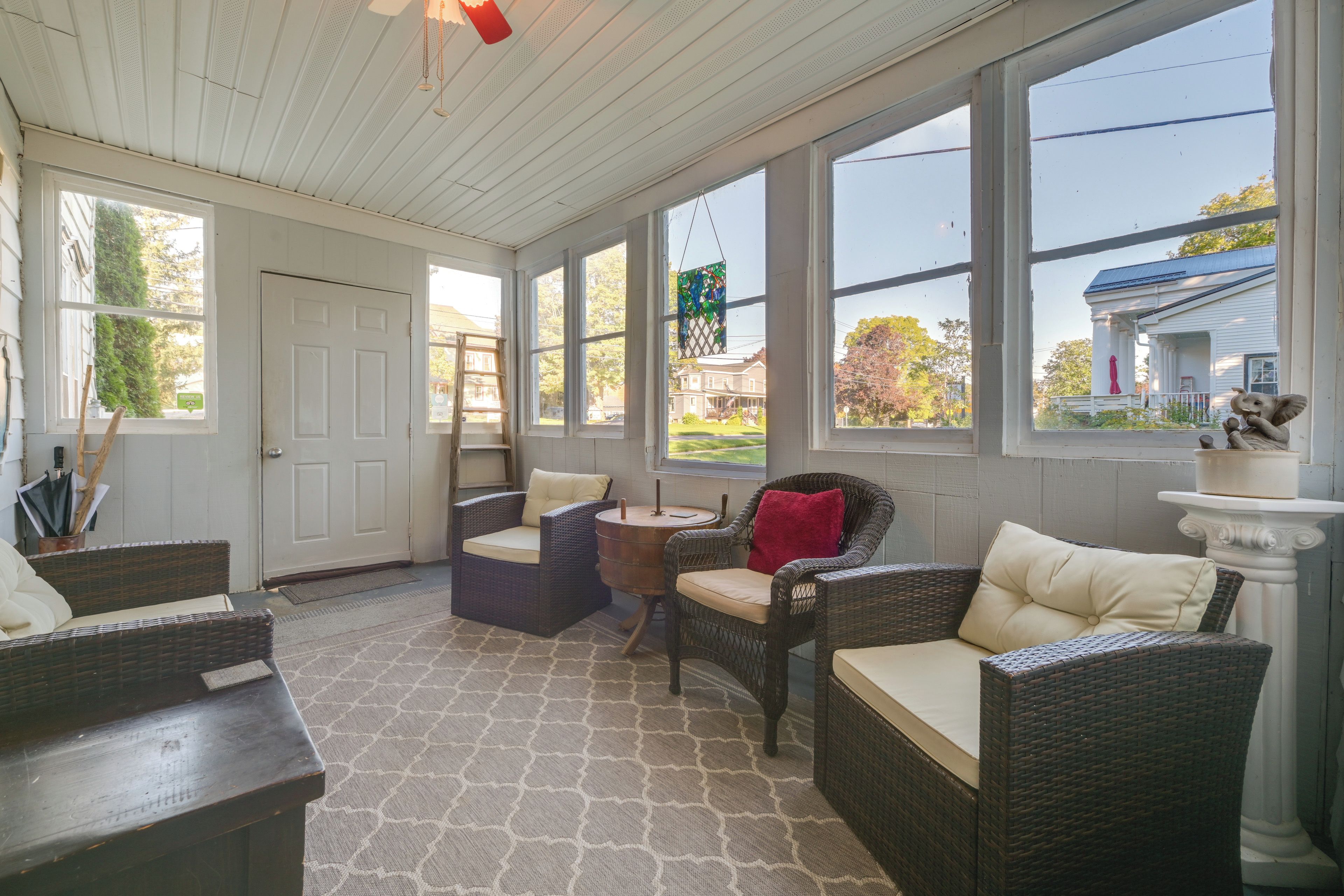 A sunroom with wicker furniture, large windows, and a view of the neighborhood.