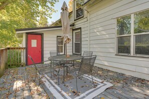 A patio with a metal table and chairs, a red door, and a covered umbrella. - Cozy B&B Suite Near Finger Lakes & State Parks (Interlaken)